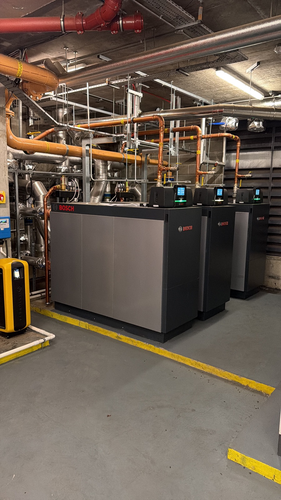 Three new Bosch commercial gas boilers in a London plant room on a Neos Engineering job, under new copper and yellow gas pipework