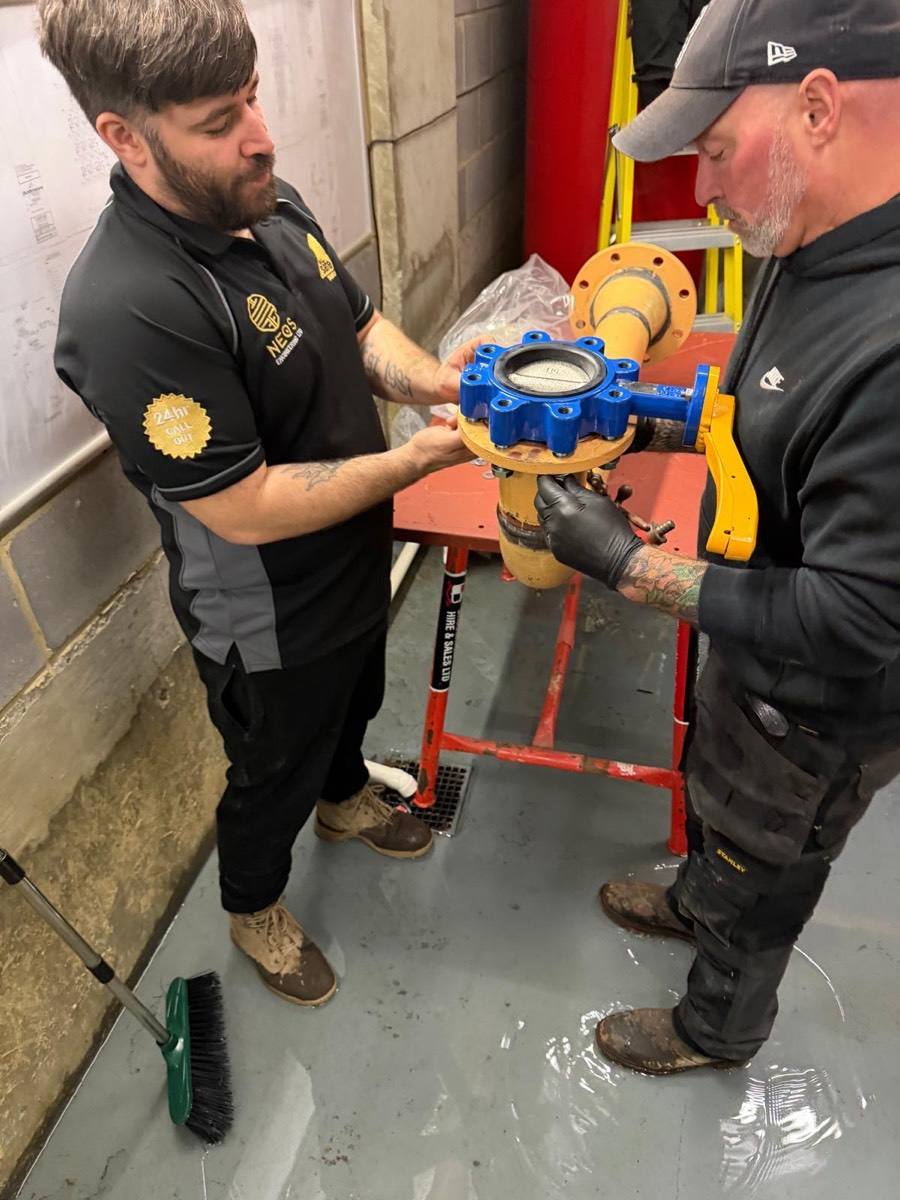 Neos Engineering engineer Clarke, left, in the Neos polo, fitting a new valve to a flanged pipe with a colleague in a commercial plant room in London